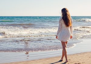 強い紫外線を浴びて海岸を歩く女性